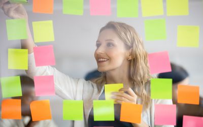 Smiling businesswoman removing sticky papers from scrum board