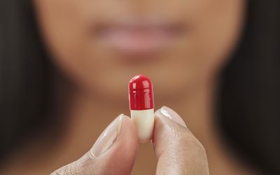 Close up of mixed race woman holding medication capsule