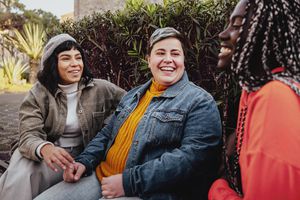 Interracial cheerful group of happy girls having fun talking together in the park talking and having fun sitting on a bench in the park 