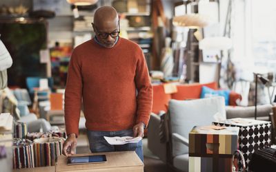 Senior man using digital tablet while reading document at store