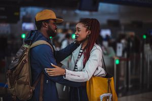 Young boyfriend and girlfriend embracing and saying goodbye at airport before airplane flight