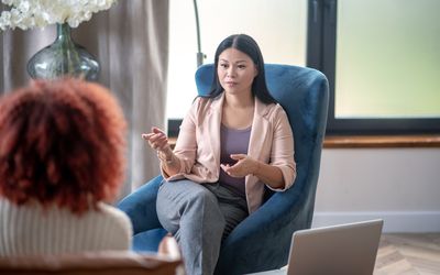 Asian professional female psychologist speaking with client