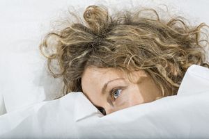 Woman in bed under white blanket