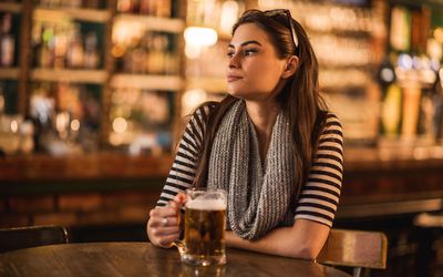 young woman sitting in a bar with a glass of beer in hand