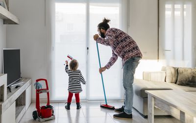 Father and little daughter cleaning the living room together