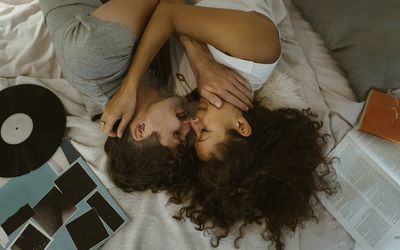 young couple lying on the led holding each other with a vinyl record next to them