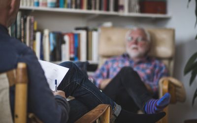 A man, sitting in a chair, talking to his psychiatrist