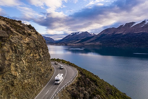 Camping car driving along the stunning lake Wakapitu between Queenstown and Glenorchy in New Zealand south island at sunset