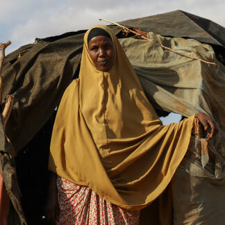 Female refugee in front of her makeshift shelter