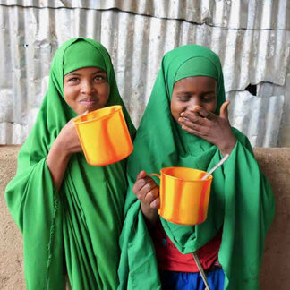 Two school girls eating nutritious school meals provided by WFP