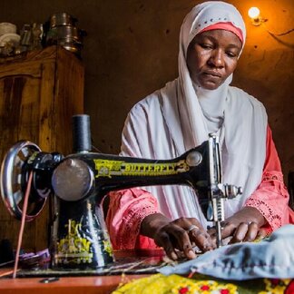 Maimuna sewing clothes at home, with the sewing machine given to her by WFP