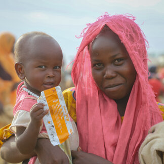 A mother and her child who is holding a WFP biscuit