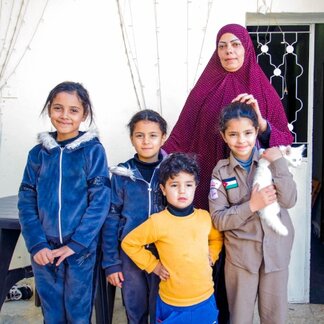 A single mother stands behind her four children, benefiting from the collaboration between WFP and the National Aid Fund under the social protection scheme.