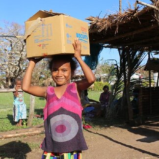 Girl carrying a ration of food item and High Energy Biscuits, as part of WFP's immediate response to Tropical Cyclone Pam.