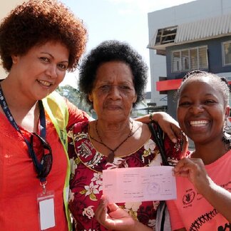 Felipa (center) receives a food voucher worth FJD 50, supported by WFP, which she can spend to buy commodities at selected outlets in Fiji in response to the Tropical cyclone Winston.