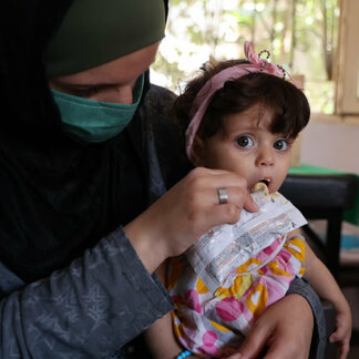 Woman feeding her child with nutrient-rich food distributed by WFP to prevent children malnutrition in Syria