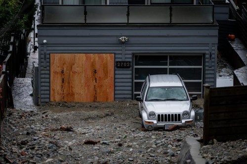 A home and vehicle are seen surrounded by debris left by flooding from torrential rain from an atmospheric river weather system at Deep Cove in North Vancouver, on Tuesday, Oct. 22, 2024. A popular park in British Columbia's Lower Mainland remains closed due to damage from an atmospheric river weather system that drenched the province's south coast, triggering a mudslide and local flooding that killed three people. THE CANADIAN PRESS/Ethan Cairns