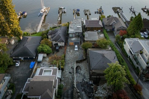 Multiple homes are seen surrounded by debris left by flooding from torrential rain from an atmospheric river weather system at Deep Cove in North Vancouver, on Tuesday, Oct. 22, 2024. Heavy rain isn't unusual for the community of Deep Cove, in North Vancouver, but when Ashifa Saferali saw an e-bike floating down the middle of the street she knew this storm was something different. THE CANADIAN PRESS/Ethan Cairns