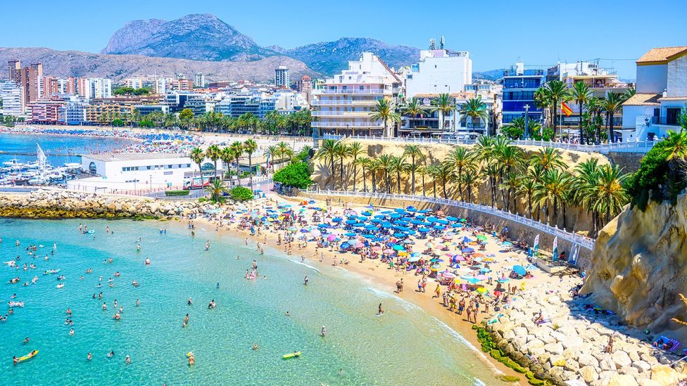 People swimming and sunbathing on a beach in Benidorm, Spain