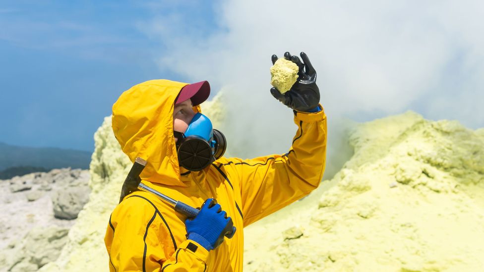 A volcanologist inspects a rock amid sulphurous volcanism (Credit: Getty Images)