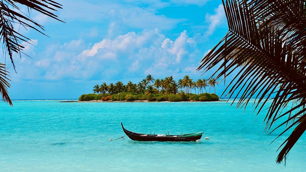 Boat in blue water in front of Kalpeni Island, Lakshadweep